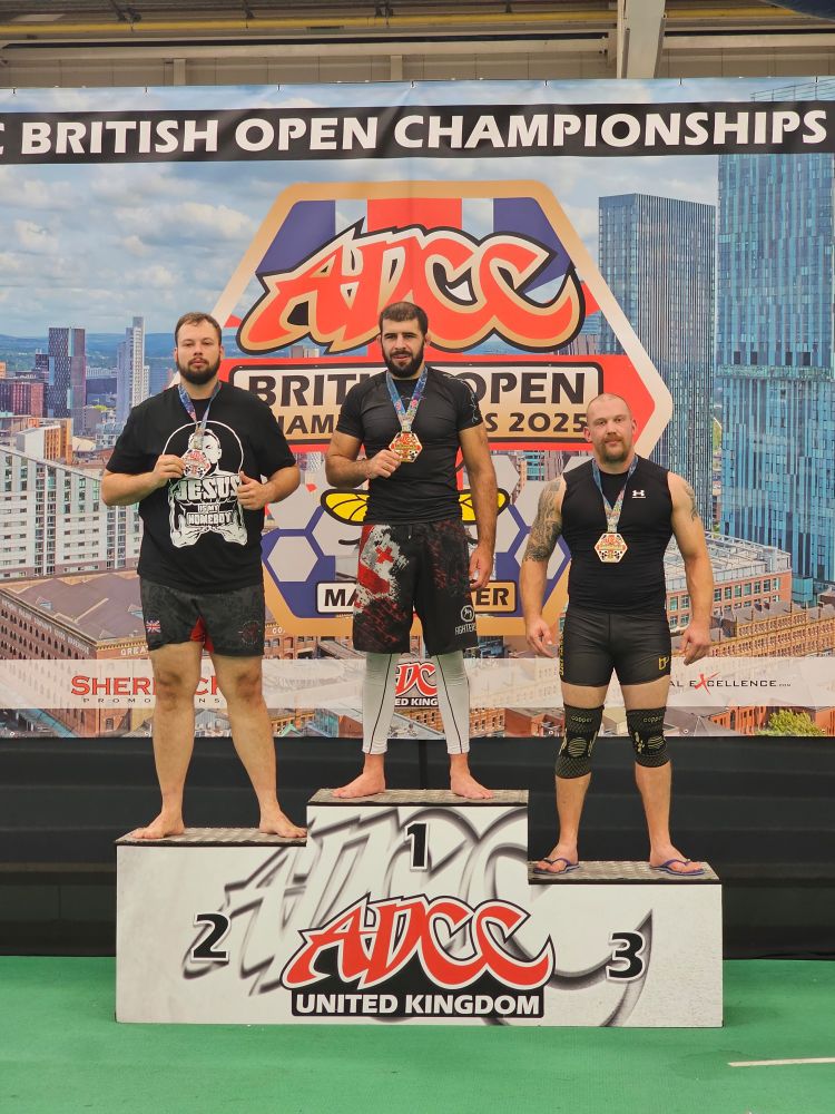 An old tired man on a podium with two very large men. 