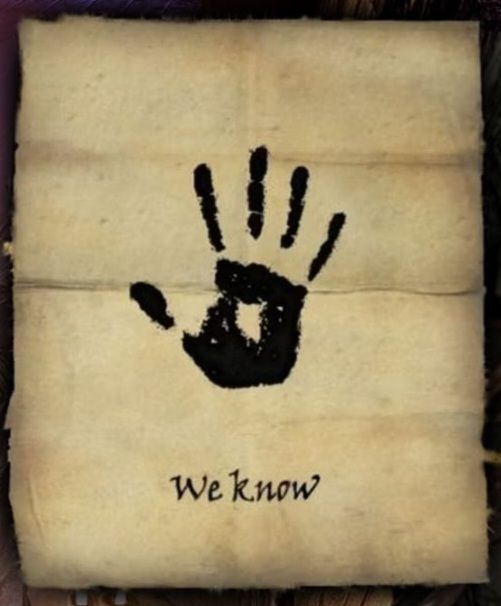 Cropped screenshot of a threatening letter on parchment with a black handprint and the words "We know" from The Brotherhood in Skyrim.