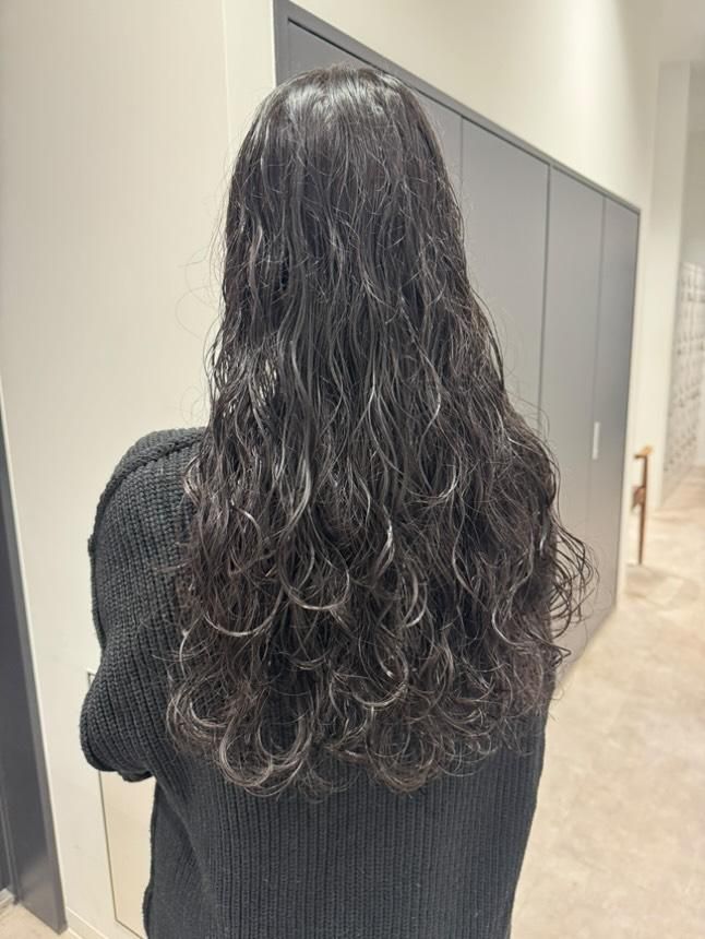 パーマをかけた後ろ姿。ロングの黒髪。