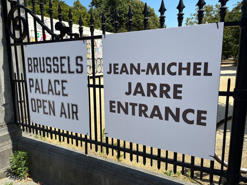 A picture of railings with signs saying “Brussels Open Air” and “Jean Michel Jarre Entrance” in English. 