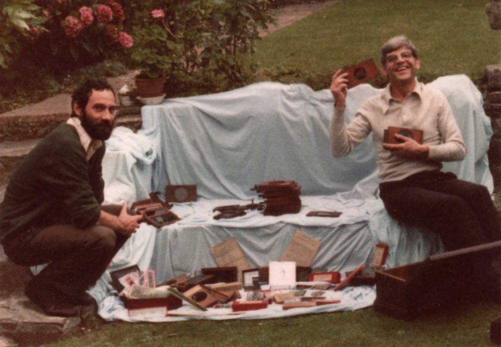 Peter Jewell and Bill Douglas in a garden with items from the moving image collection. 