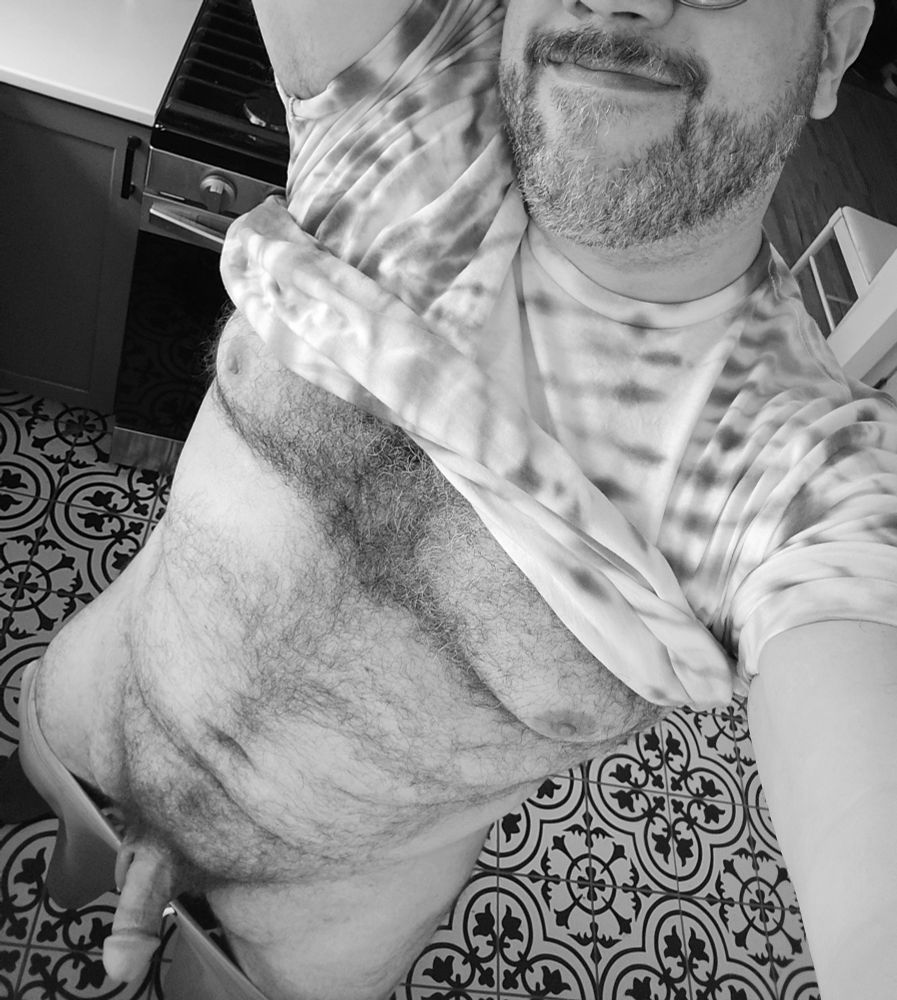 Chubby guy in grayscale. Tie dye shirt pulled up. Shorts pulled down. Tits, belly, and dick on show