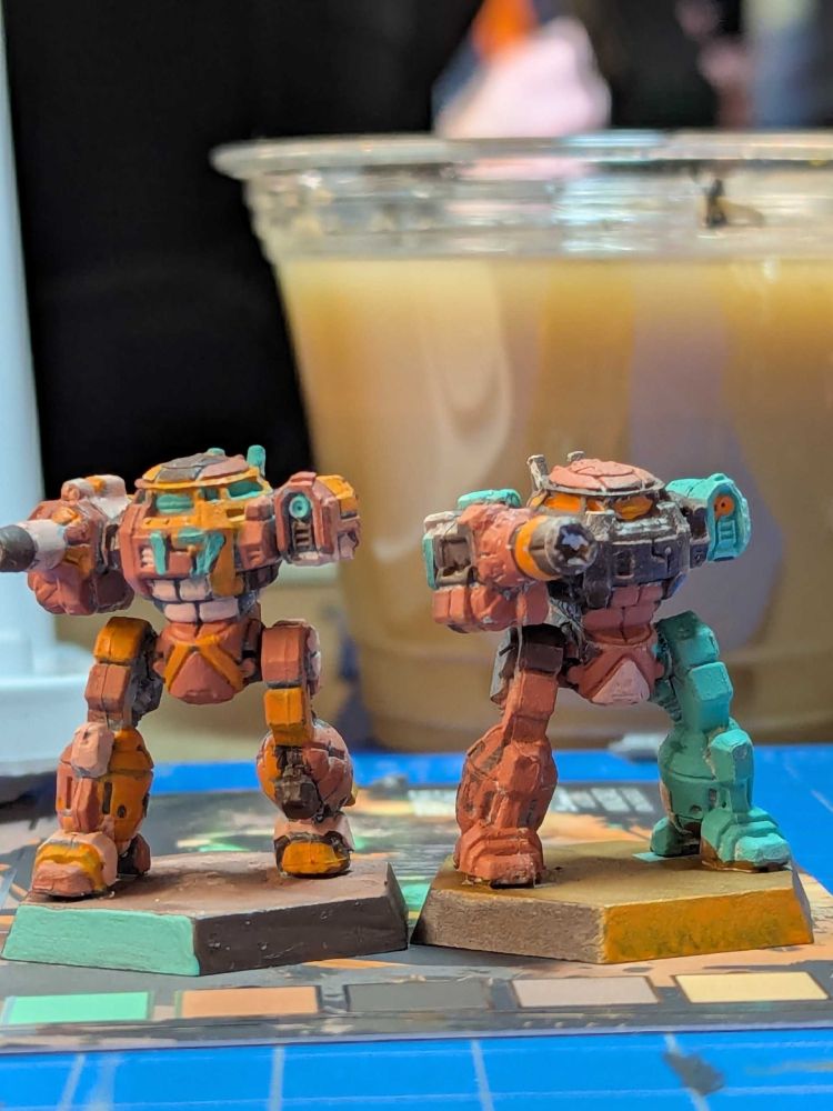 Front pic of two UrbanMechs painted in Mint Green, Orange, Brown, Terra Cotta Red and Pink.