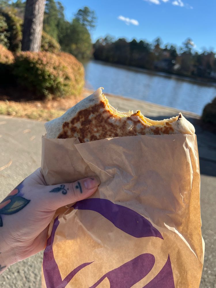 Crunchwrap from Taco Bell with lake in the background   