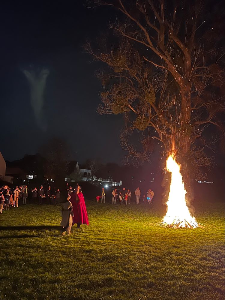 Огън на открито, човек, облечен като Св. Мартин с червена мантия, в кръг наредени деца с фенери и семействата им