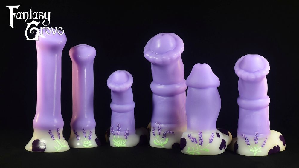 A lineup of dildos with a soft lavender shaft, white base, dark purple cow spots on the base, and lavender plants hand painted on the base and up into the shaft. From left to right there's a medium and large simplified equine model, a small and large chunky equine model, a stout humanoid model, and a medium chunky equine model.