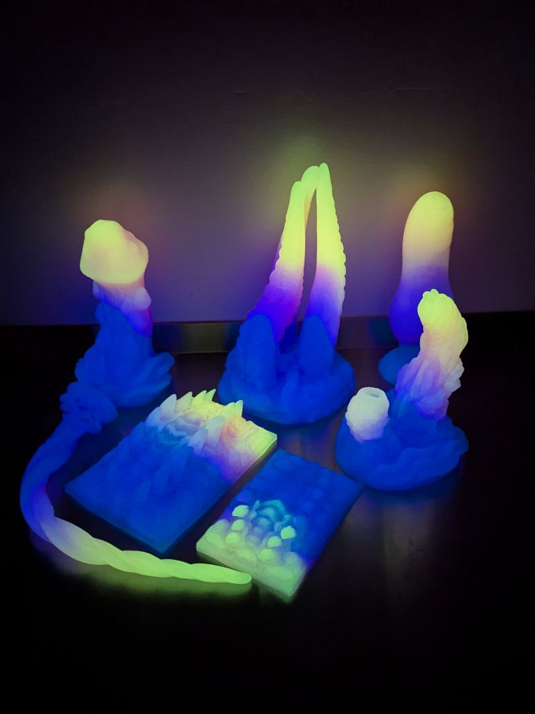 The same toys glowing in the dark in a fade of yellow to purple to blue