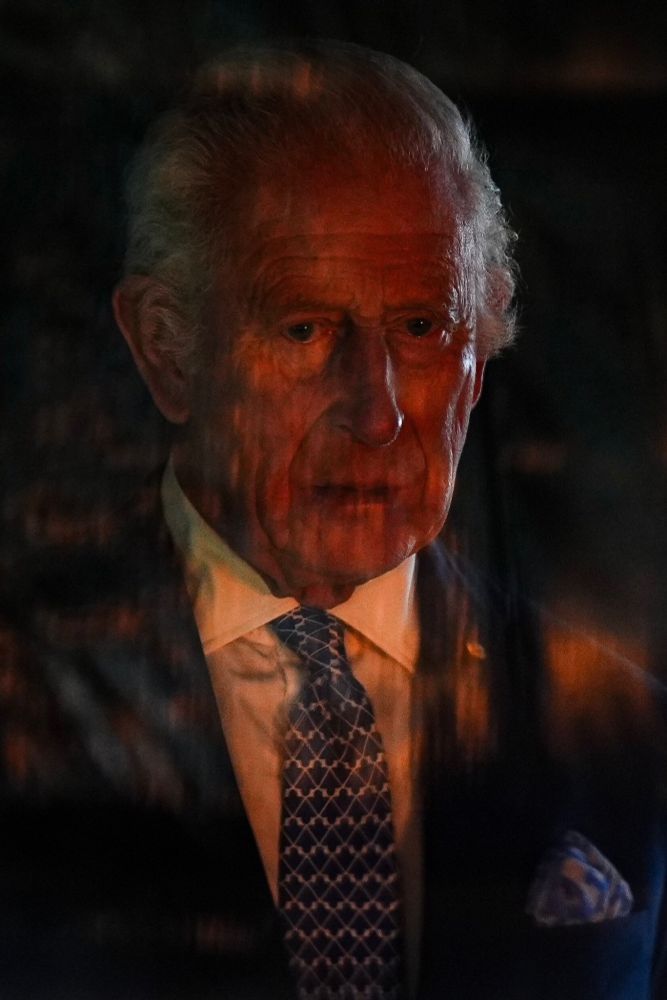 Le roi D'Angleterre qui tire une gueule abyssale. Des flammes se reflettent dans la vitre juste devant lui, se surimpressionnant sur lui.