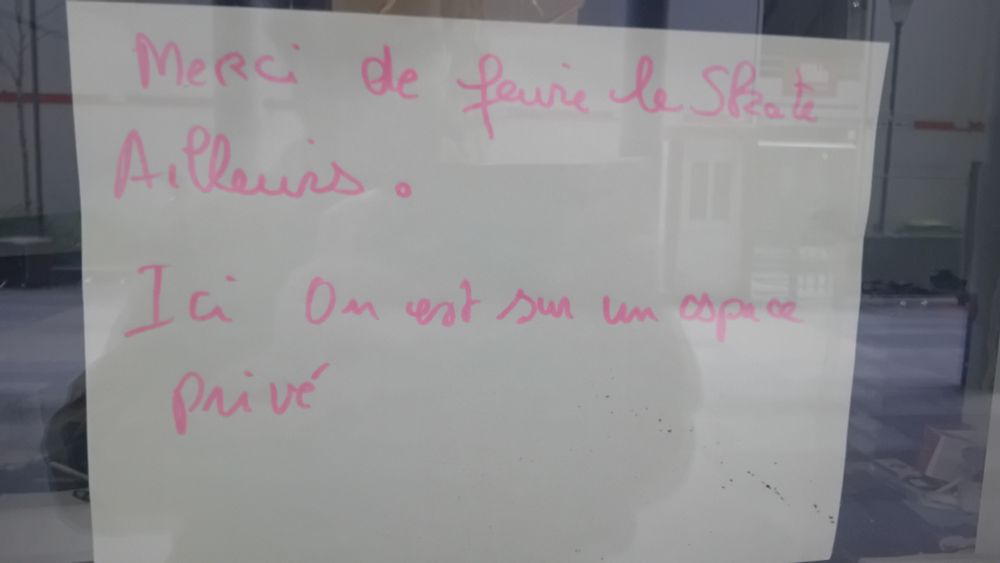 Feuille collée derrière une vitre où est écrit au feutre rose
 "Merci de faire le Skate Ailleurs .
Ici  On est sur un espace privé" 
