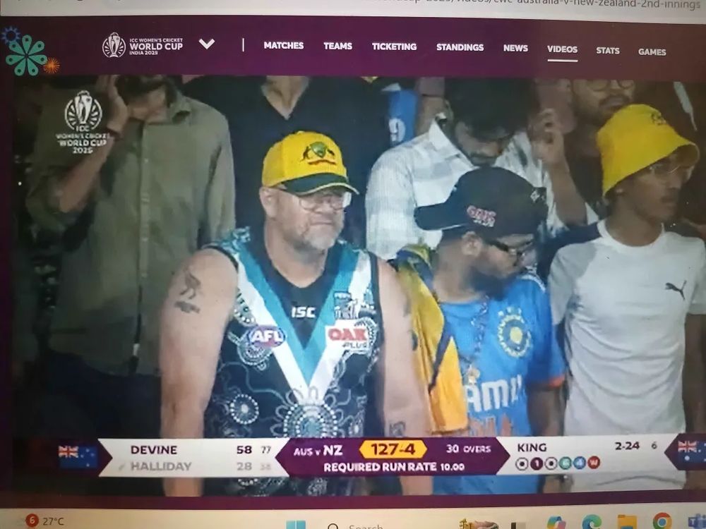 A middle-aged Aussie bloke watching a women's World Cup match in India wearing Port Adelaide's indigenous guernsey