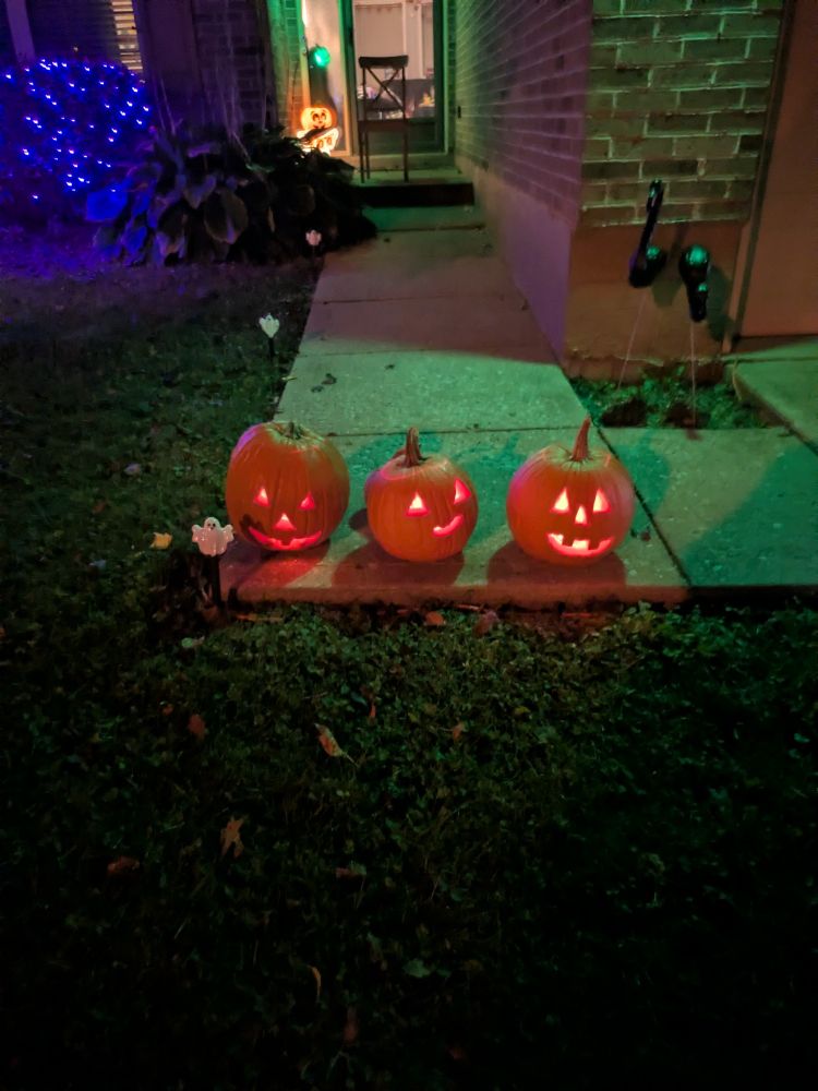 Three pumpkins flicker in the darkness