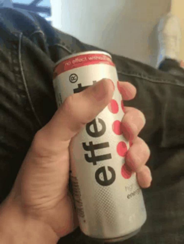 a person is holding a can of effervescent energy drink in their hand