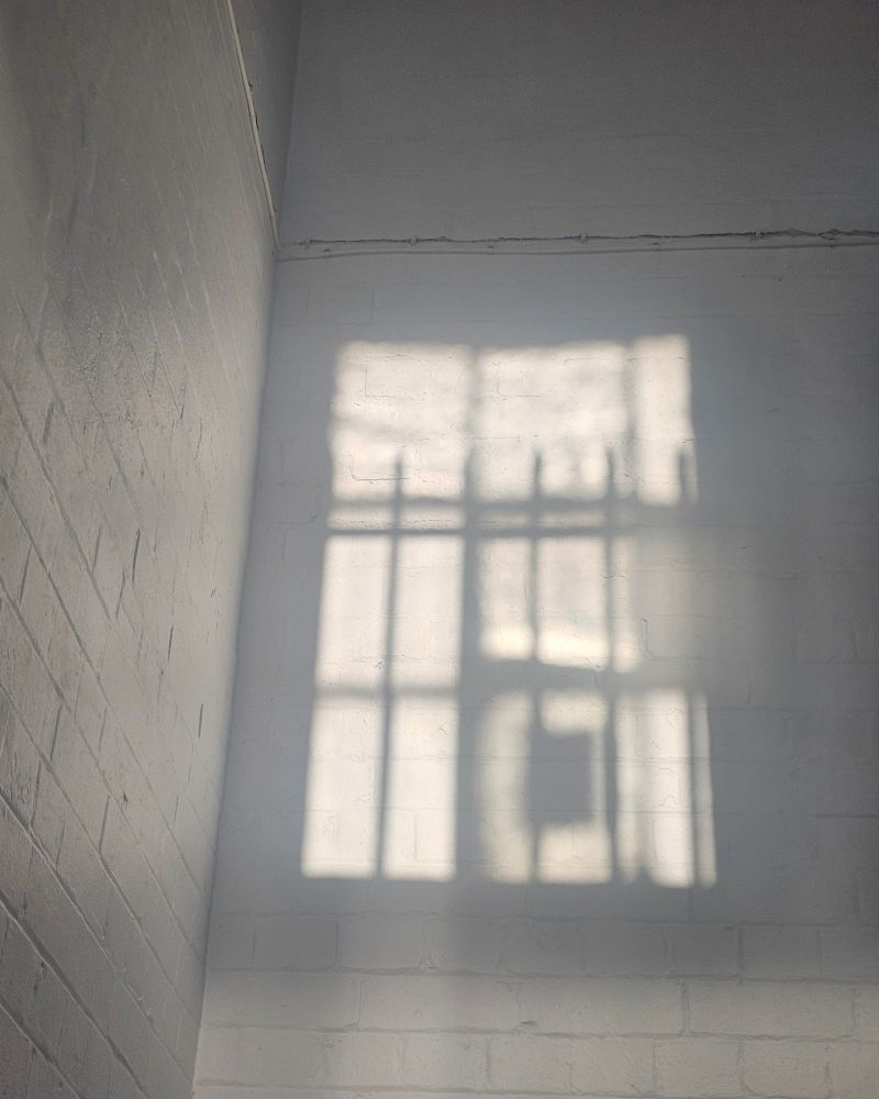A shadow of a window on a brick wall that's been painted white 
