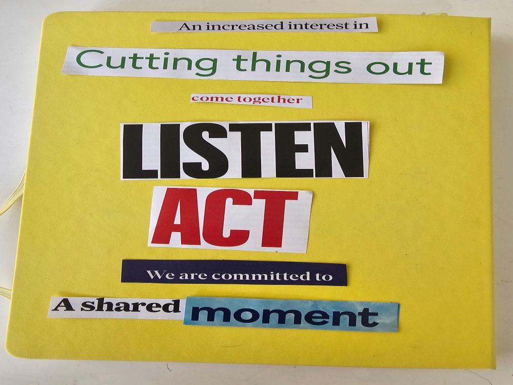 A yellow hard covered notebook with words and phrases sliced from magazines placed on top. 