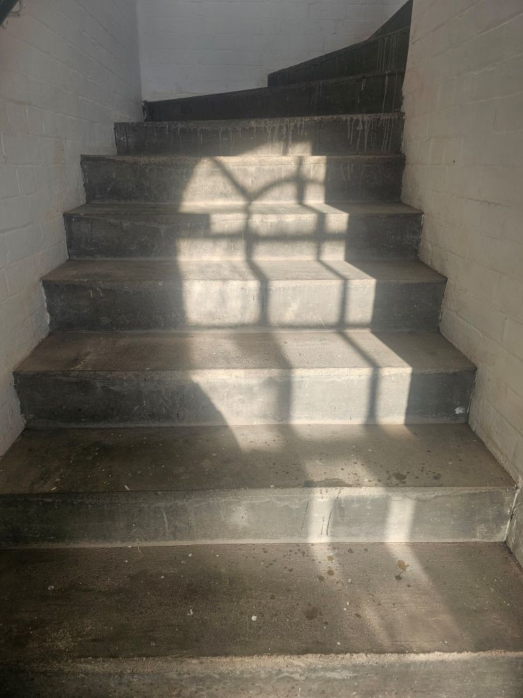 Stone steps with a reflection of an arched window stretching across them 