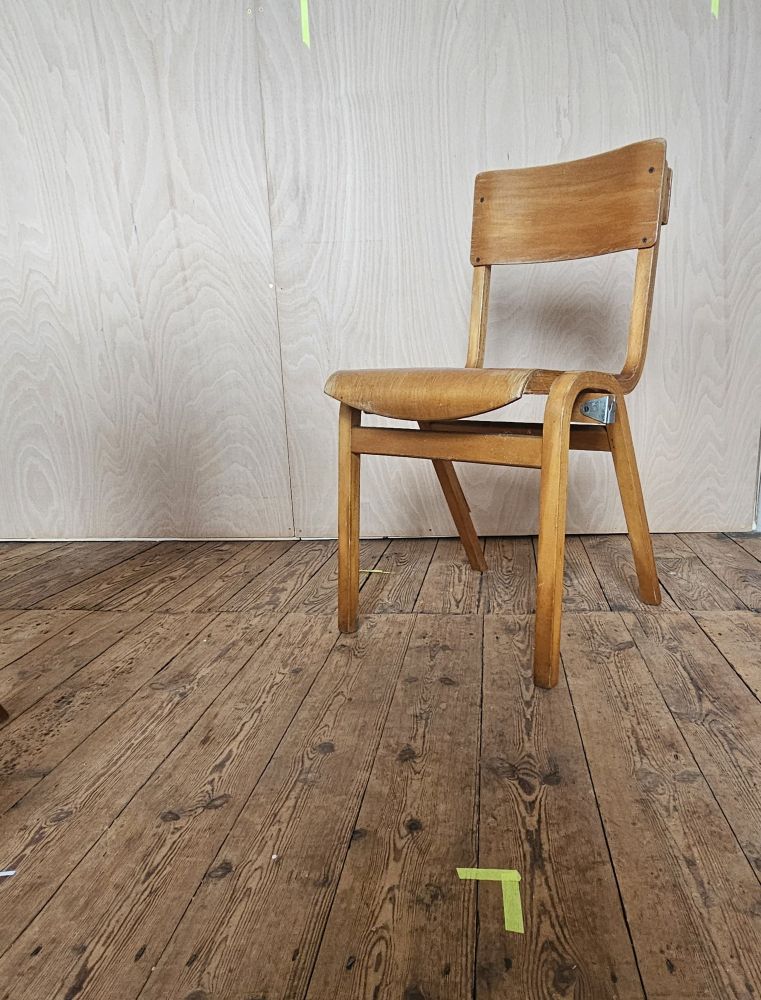 A wooden chair on a wooden floor in front of a wooden wall 