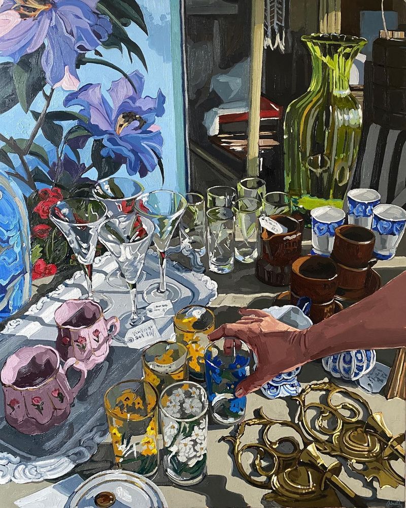 Pintura al oleo de estilo realista. Muestra un puesto de un mercadillo en un plano medio superior. el puesto está lleno de piezas de cristal, cerámica y piezas decorativas. Desde la mitad del margen izquierdo se ve un brazo que está a punto de agarrar de modo delicado un vaso de cristal que está en el centro de la imagen.