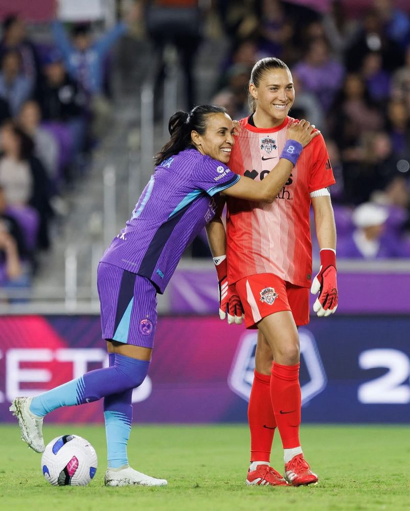 Marta leans across Aubry in a casual hug.