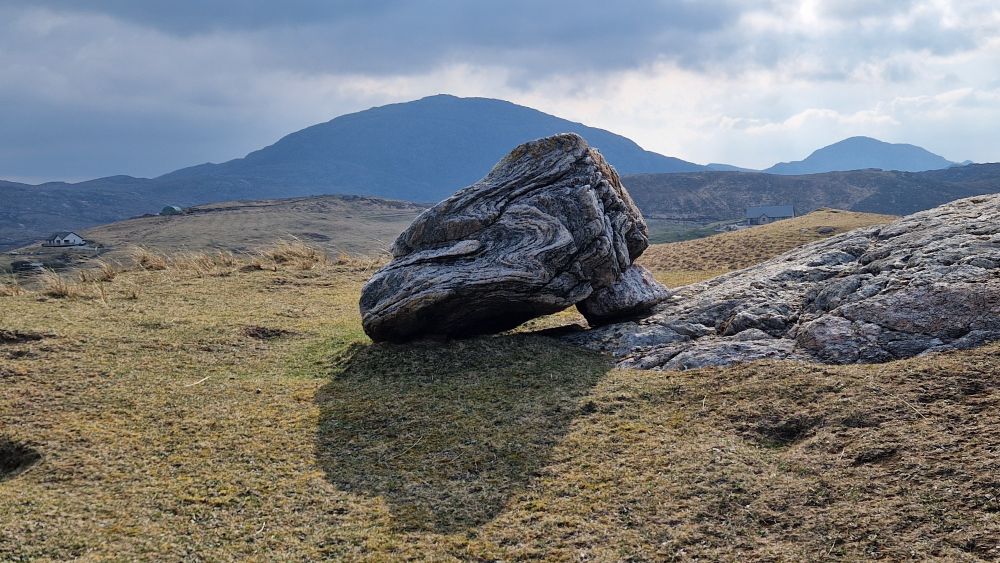 A bolder of gneiss with a hill in the background
