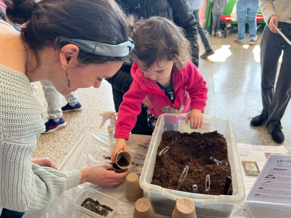 A young participant plants lettuce seeds in lead-free potting soil at the Family Fun and Disability Awareness Fair.