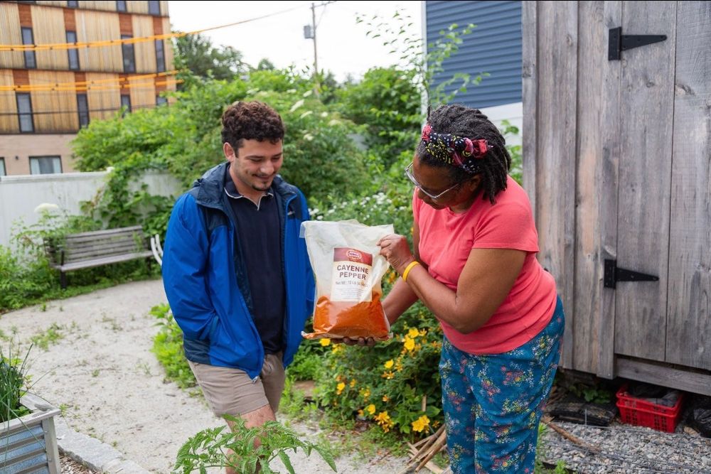 Ben Weitz, recent MS graduate and community engagement core student worker, looks at a bag of cayenne pepper with Mary Ann Nelson, president of the Mission Hill Health Movement.