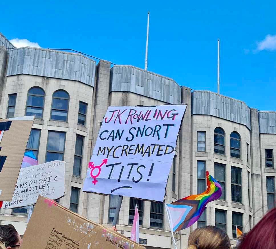 Cardboard sign at protest that reads ‘JK Rowling can snort my cremated tits’