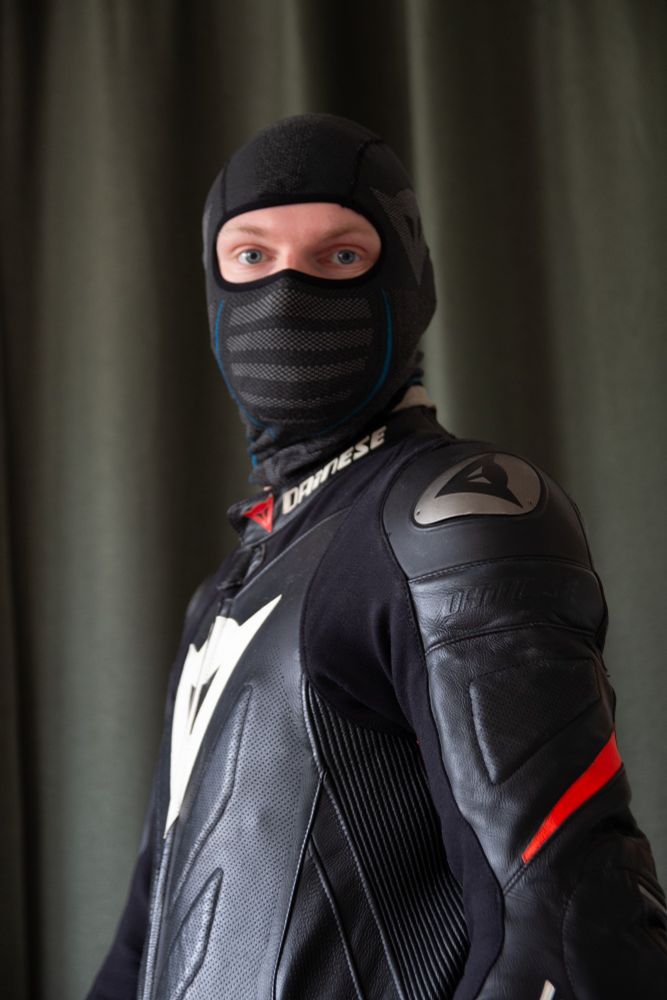 Me in a biker suit and balaklava, body facing to the left, while looking at the camera. 