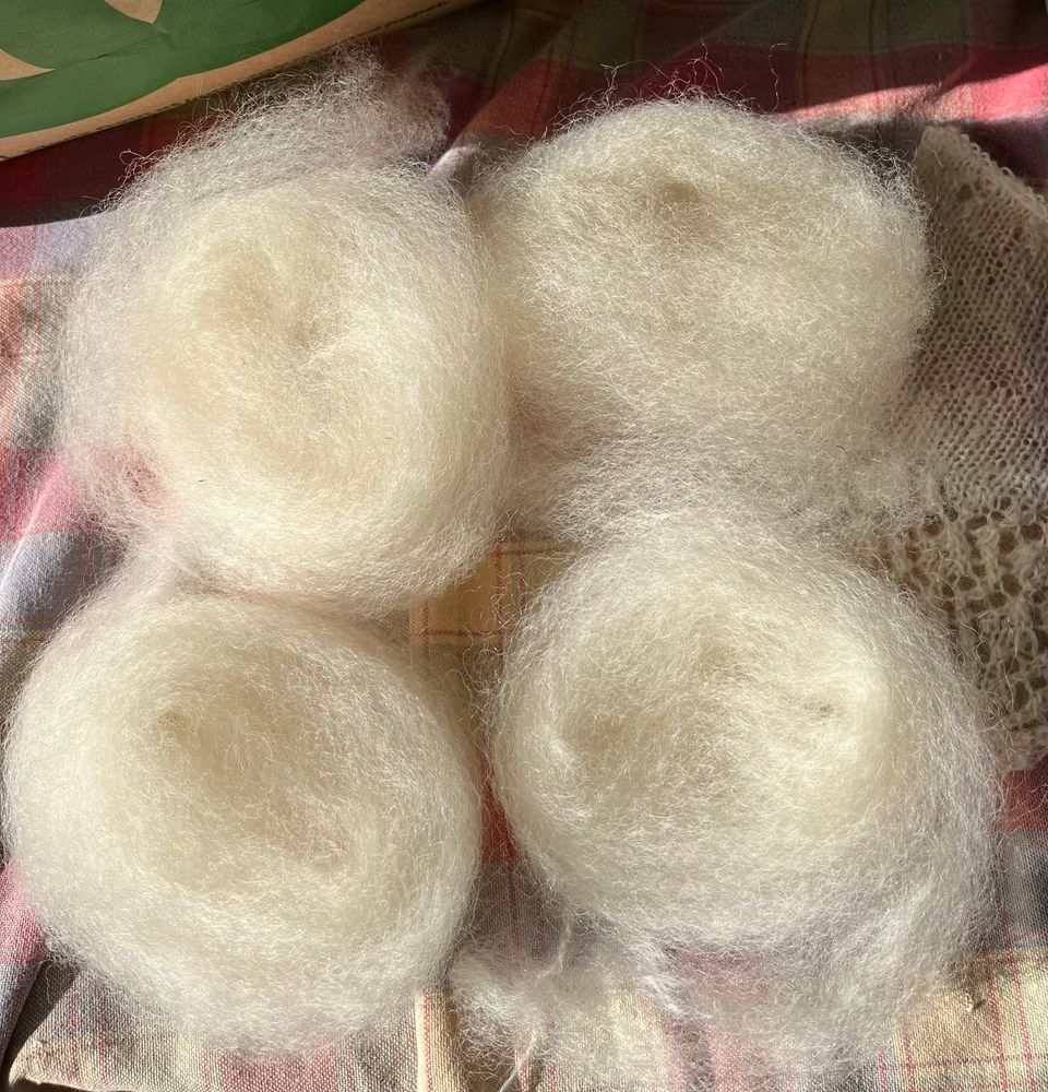 Photo of four floof balls made up of a blend of unwashed East Friesian/Perendale and Romney/Polwarth.