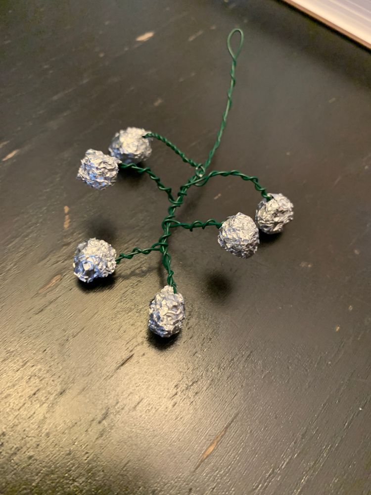 A photo of a wire armature fashioned to look like a branching cluster of tomatoes. Aluminum balls are wadded at the end of each stem.