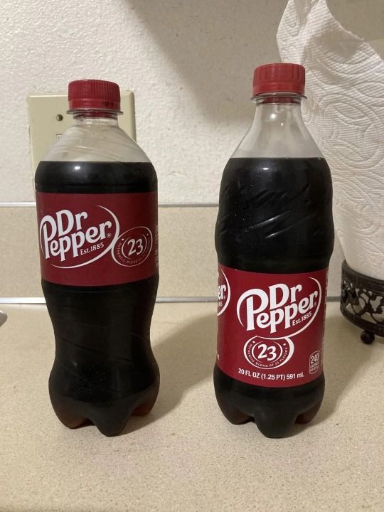 a dr. pepper bottle distributed by pepsi on the left, a dr. pepper bottle distributed by coke on the right