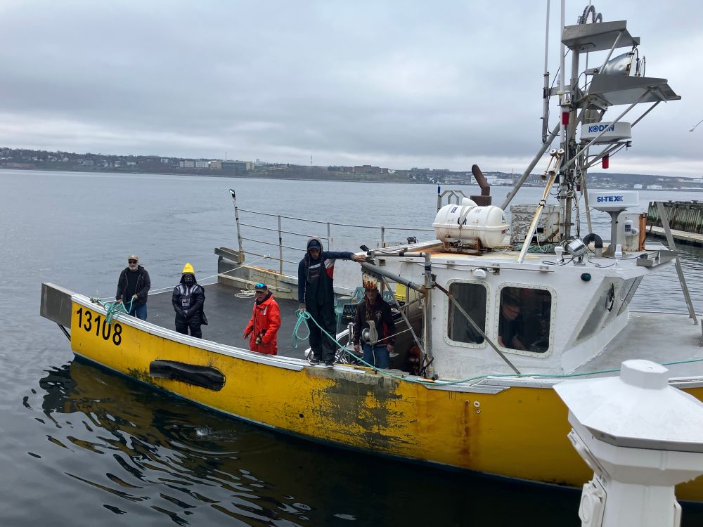 A yellow fishing boat with several people aboard including one dressed as Darth Vader wearing a sou’wester. 