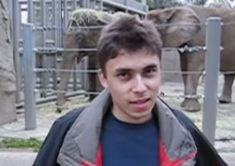 A still frame from the video. Jawed Karim is standing in front of the elephants at the San Diego Zoo.