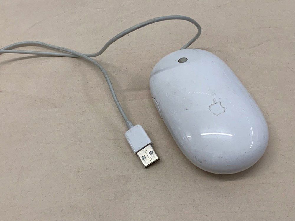 a wired Mighty Mouse sitting on a table.