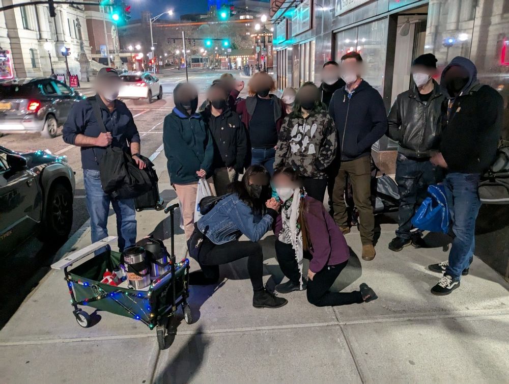 A group of 13 comrades pose in Providence next to a cart decorated with xmas lights