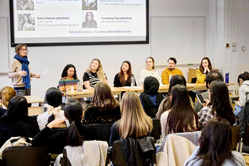 A panel sit at the front of a room of onlookers at an event