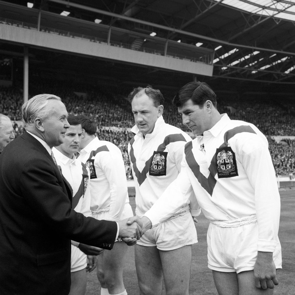 Rugby players line up on the pitch to shake hands with Howard Wilson, British Prime Minister