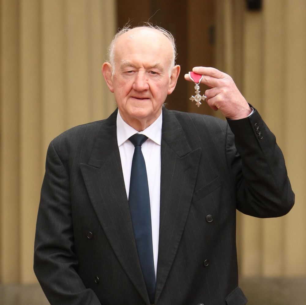 Ray French holds up his MBE medal
