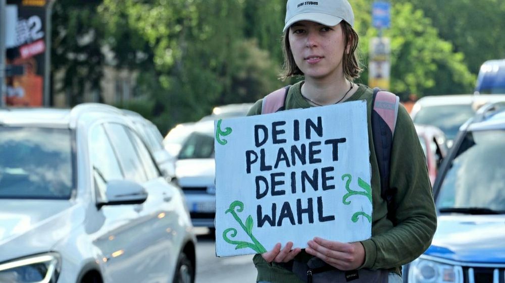Eine junge Frau trägt ein Schild. Dein Planet, deine wahl