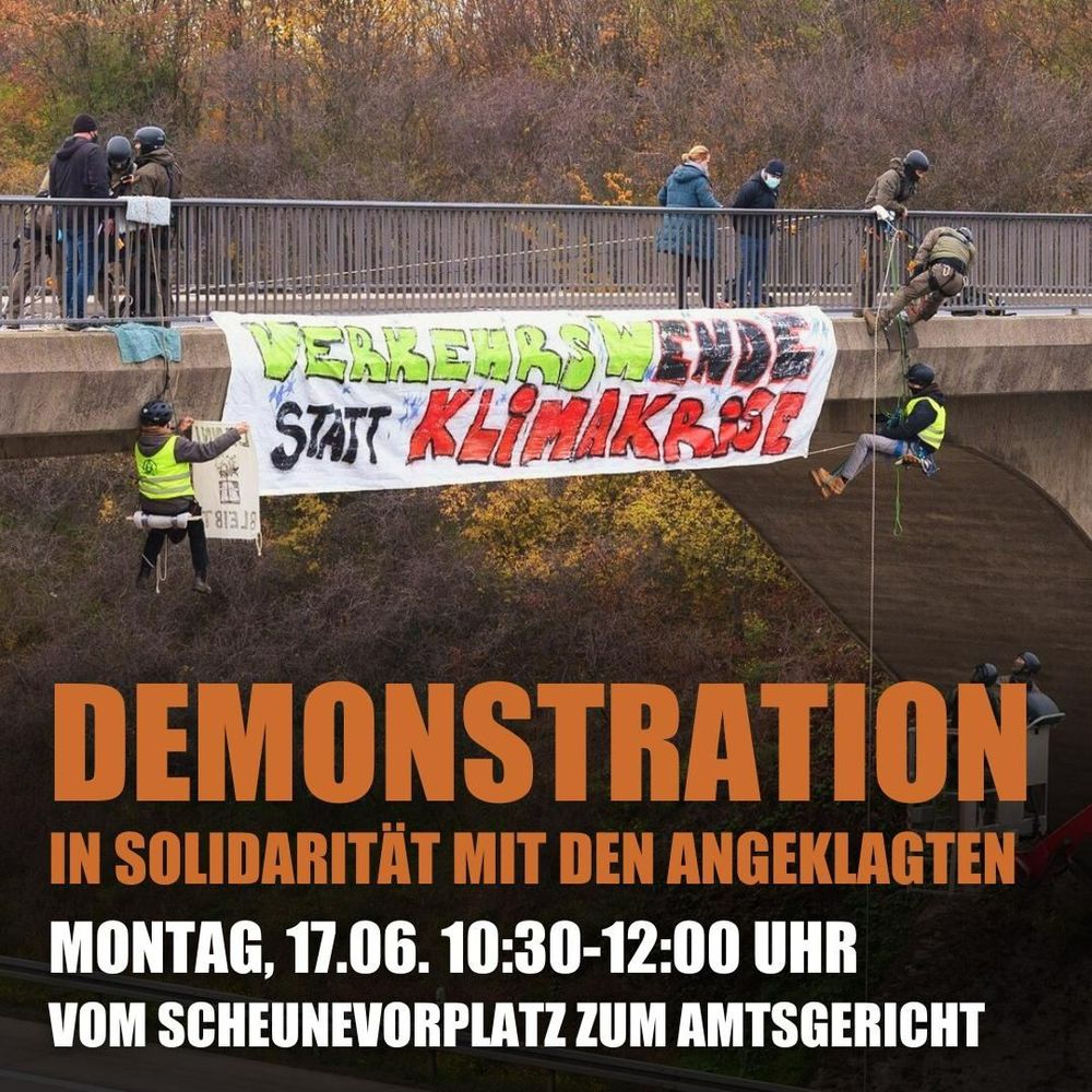 Menschen hängen an einer Autobahnbrücke und halten ein Transparent mit den Worten „Verkehrswende statt Klimakrise“.