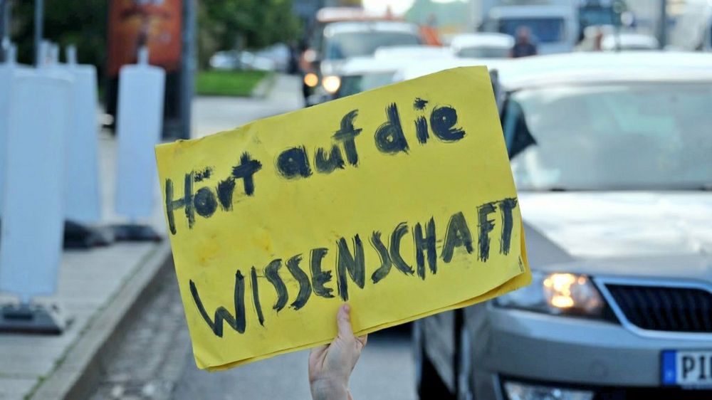 Ein Schild: hört auf die Wissenschaft