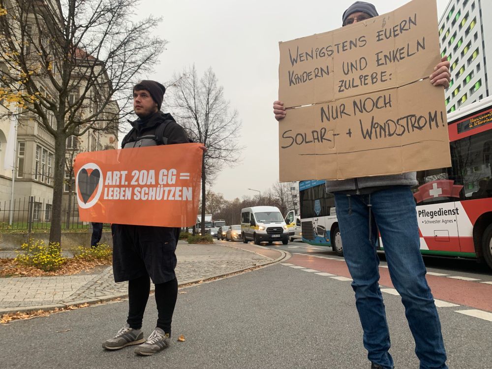 Menschen blockieren den Fritz-Foerster-Platz in Dresden. Sie halten Banner mit dem Text „Wenigstens euern Kindern und Enkeln zuliebe“ für Erneuerbare Energien.