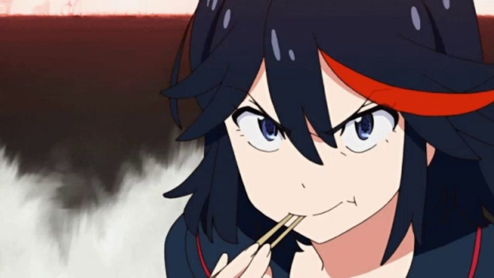 a girl with black hair and red highlights is eating something with chopsticks