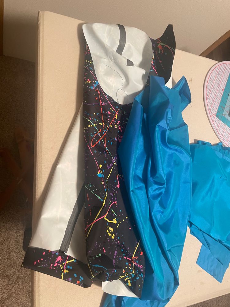 two sets of disembodied sleeves, one in taffeta lining and one in waterproof multi color splatter paint fabric.