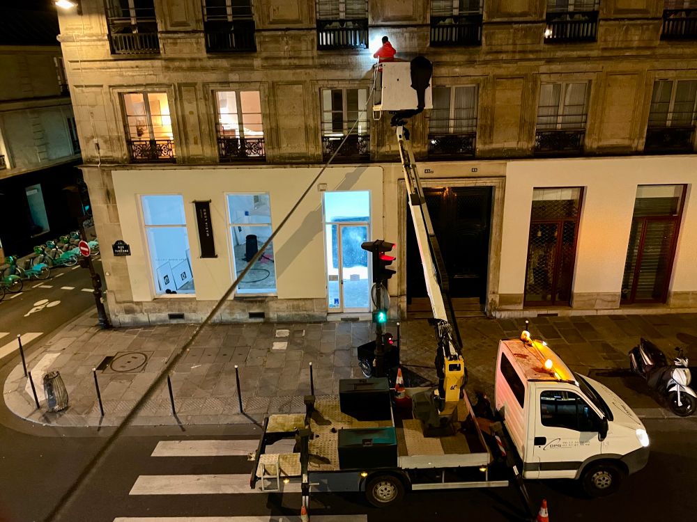 A city worker in a cherry picker hanging up the wire that will old the Christmas lights. 