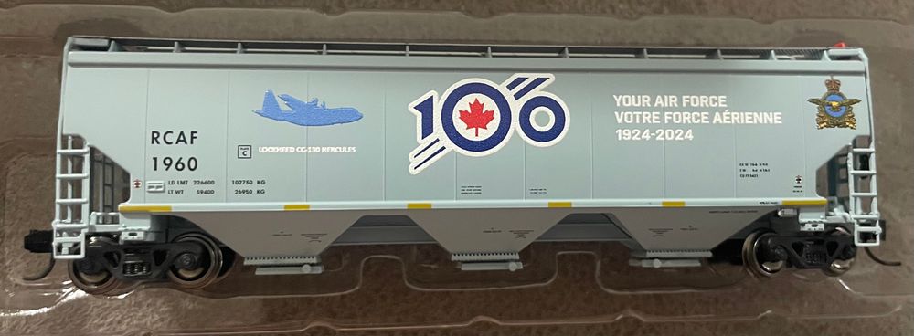 RCAF commemorative 5431 cu.ft. hopper car. It’s painted in grey with the RCAF 100 logo in red, white and blue. The phrase “Your Air Force, Votre Force Aérienne, 1924-2024” in white on three lines.

A silhouette of a CC-130 Hercules is in light blue is on the side with the identification marks RCAF 1960 in black.