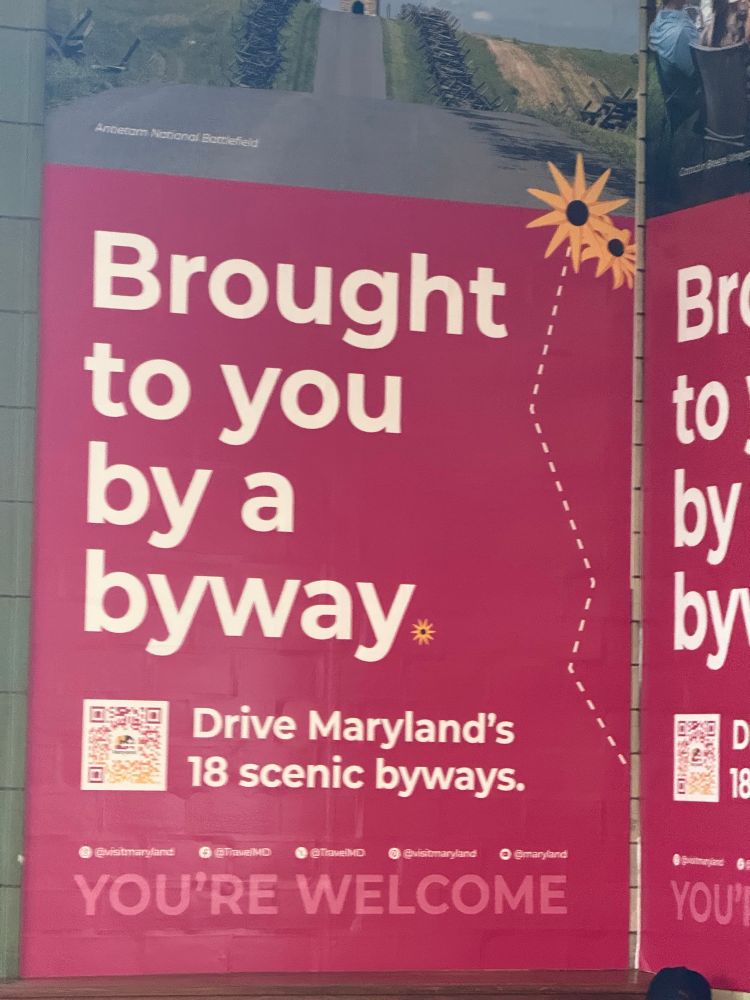 Large red poster with mostly white text: "Bright to you by a byway. Drive Maryland's 18 scenic byways. You're welcome."