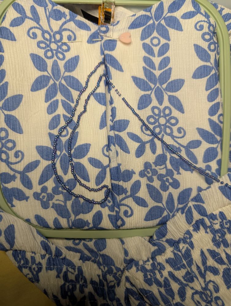 Photo of the front of a dress that has some handsewn embellishments being added to form the shape of a leaf.
