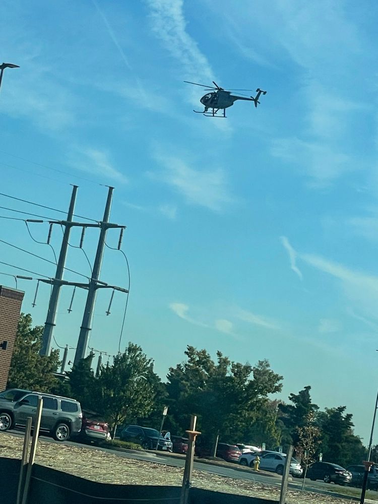 Brown unmarked helicopter hovering over shopping center