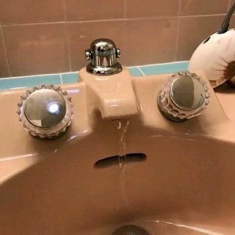 A pink bathroom faucet that’s running water, the taps and drainage hole make a face making it look like it has a runny nose