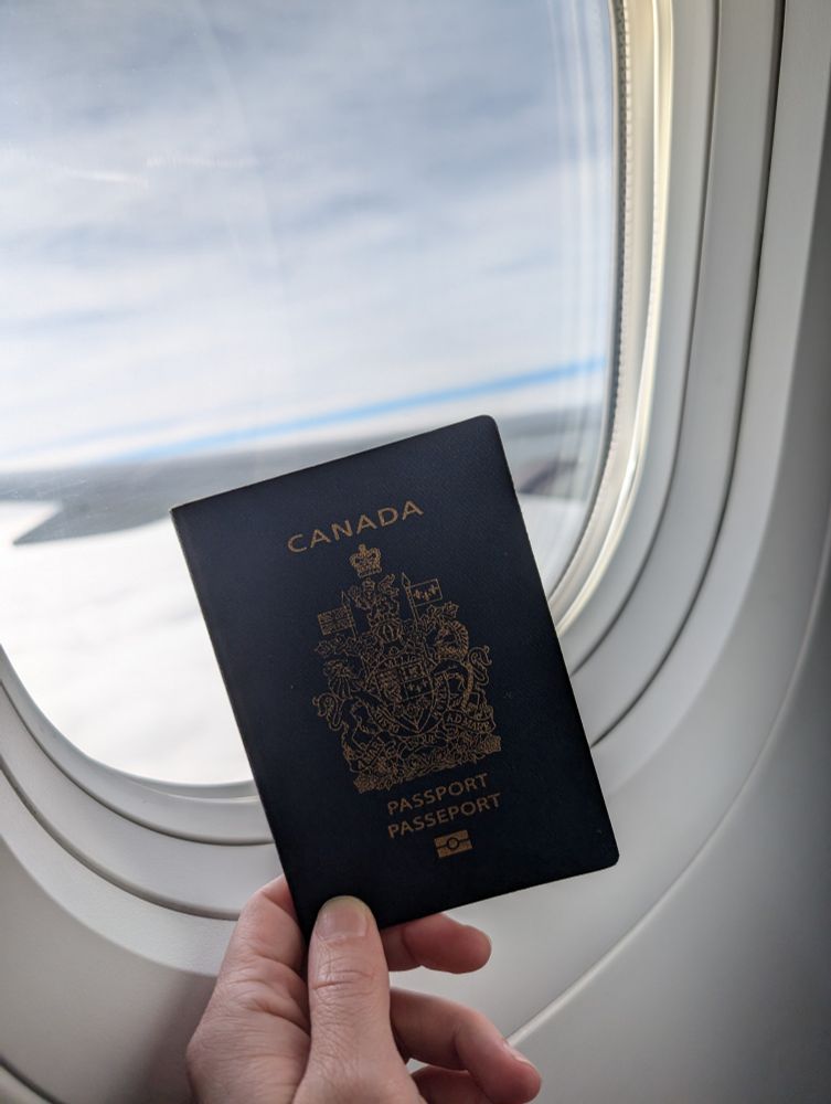 Passport held up to a plane window. 